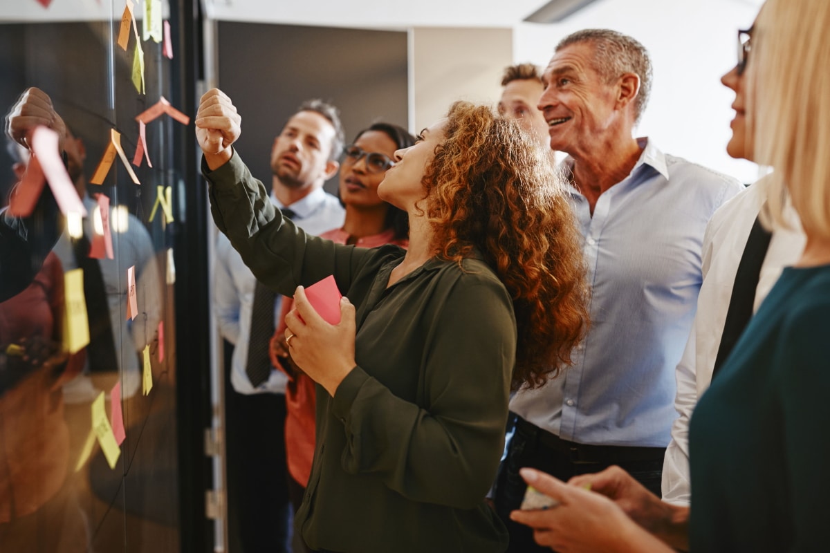 workshop-agilitaet-erleben-header Frau erklärt ihrem Team anhand von Post-its